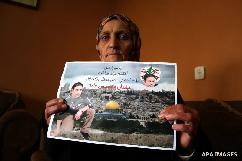 The mother of the prisoner Haitham Ezzat Salheyah carrying a picture of him in the West Bank city of Ramallah January 19, 2011, the prisoner escaped an assassination attempt by the Israeli "Shabak" through customer tried...