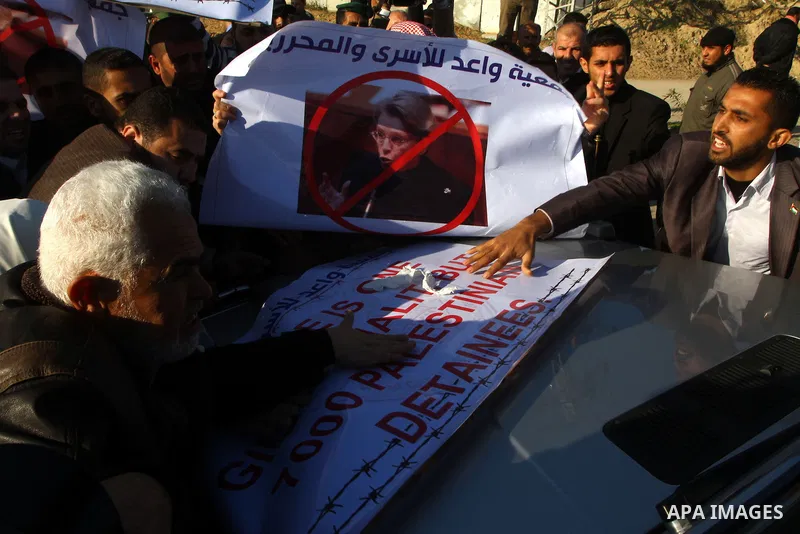 Palestinian relatives of a prisoners jailed in Israel hold posters as they block the vehicle carrying French Foreign Minister Michele Alliot-Marie as it makes its way into Gaza Strip, on the Palestinian side of the Erez...