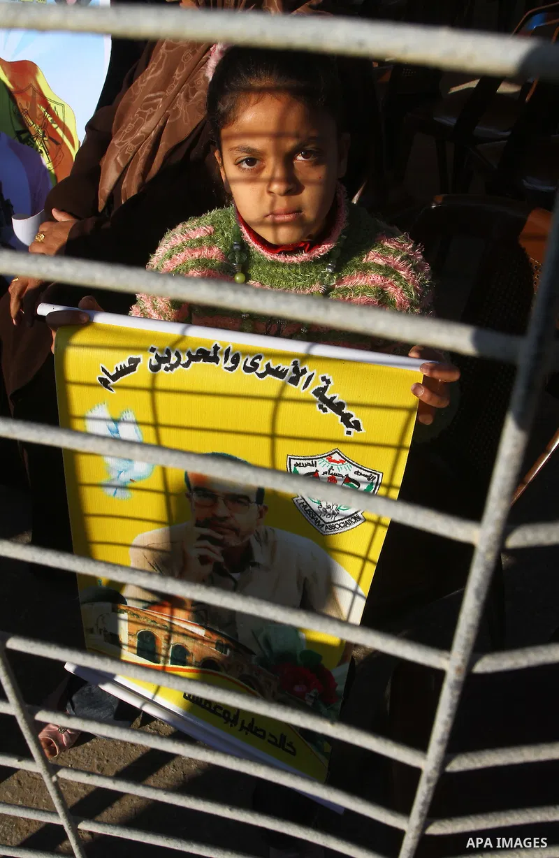Palestinian relatives of a prisoners jailed in Israel hold pictures of prisoners as they block the vehicle carrying French Foreign Minister Michele Alliot-Marie as it makes its way into Gaza Strip, on the Palestinian sid...