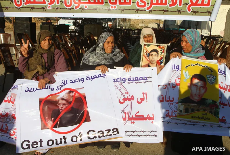 Palestinian relatives of a prisoners jailed in Israel hold posters as they block the vehicle carrying French Foreign Minister Michele Alliot-Marie as it makes its way into Gaza Strip, on the Palestinian side of the Erez...