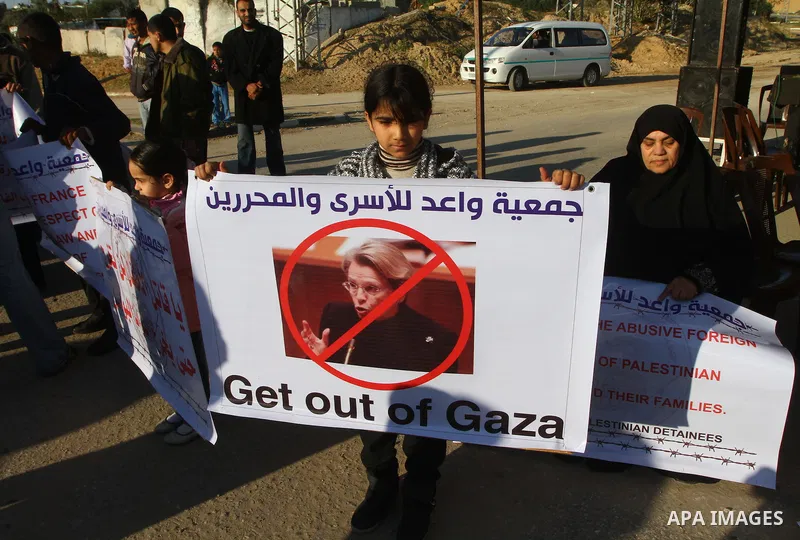 Palestinian relatives of a prisoners jailed in Israel hold posters as they block the vehicle carrying French Foreign Minister Michele Alliot-Marie as it makes its way into Gaza Strip, on the Palestinian side of the Erez...