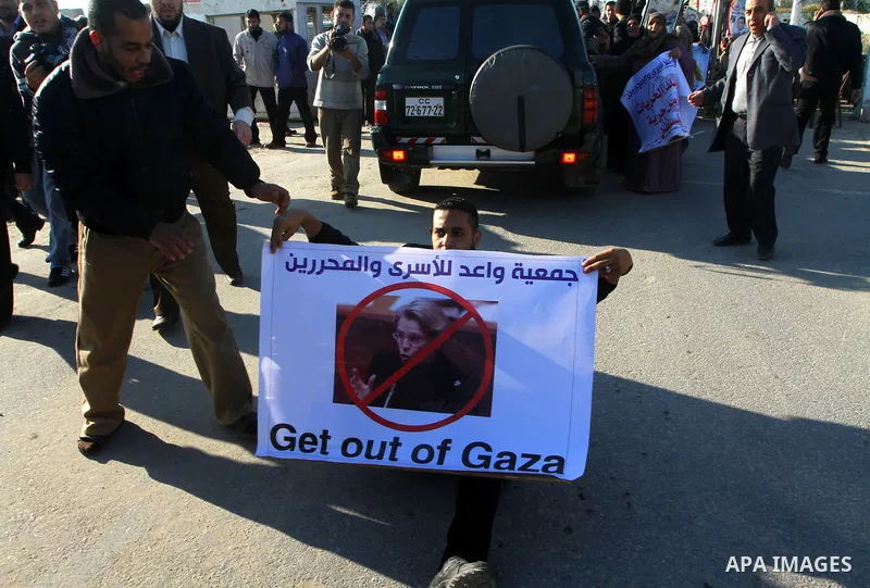 Palestinian relatives of a prisoners jailed in Israel hold posters as they block the vehicle carrying French Foreign Minister Michele Alliot-Marie as it makes its way into Gaza Strip, on the Palestinian side of the Erez...