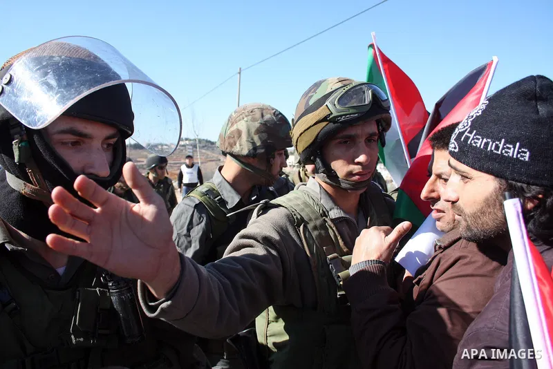 Israeli soldiers stand guard as Palestinian, Israeli and foreign protesters take part in a demonstration against Israel's controversial separation barrier in the West Bank village of Maasarah, near Bethlehem, on January...