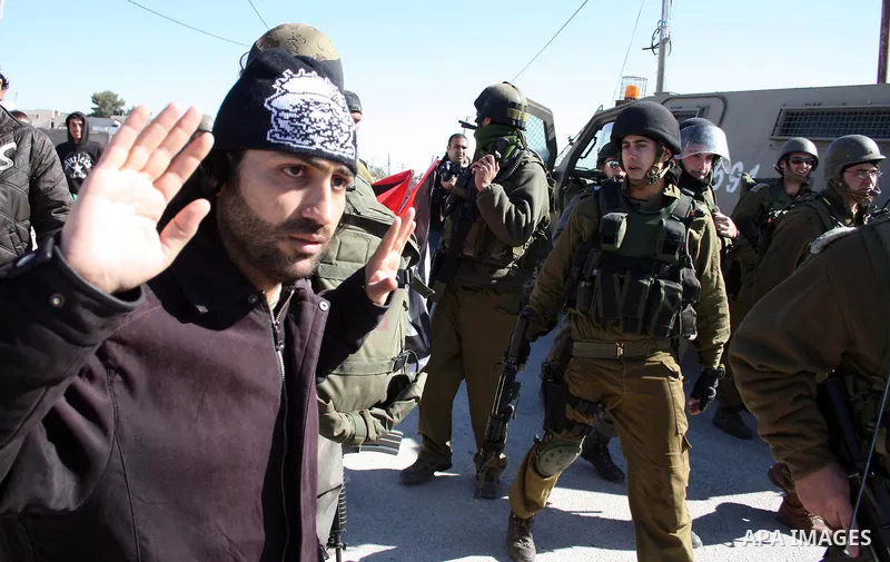 Israeli soldiers stand guard as Palestinian, Israeli and foreign protesters take part in a demonstration against Israel's controversial separation barrier in the West Bank village of Maasarah, near Bethlehem, on January...