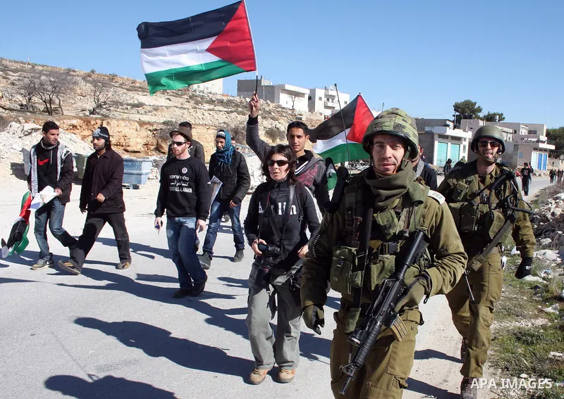 Israeli soldiers stand guard as Palestinian, Israeli and foreign protesters take part in a demonstration against Israel's controversial separation barrier in the West Bank village of Maasarah, near Bethlehem, on January...