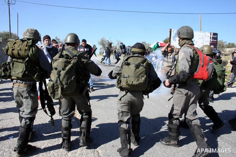 Israeli soldiers stand guard as Palestinian protesters take part in a demonstration against the expansion of the nearby Jewish settlement of Halamish in the West Bank village of Nabi Saleh, near Ramallah, Friday, Jan. 21...