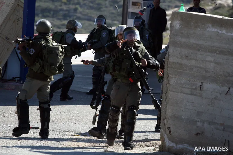 An Israeli border police officer fires tear gas at Palestinian protesters during a demonstration against the expansion of the nearby Jewish settlement of Halamish in the West Bank village of Nabi Saleh, near Ramallah, Fr...