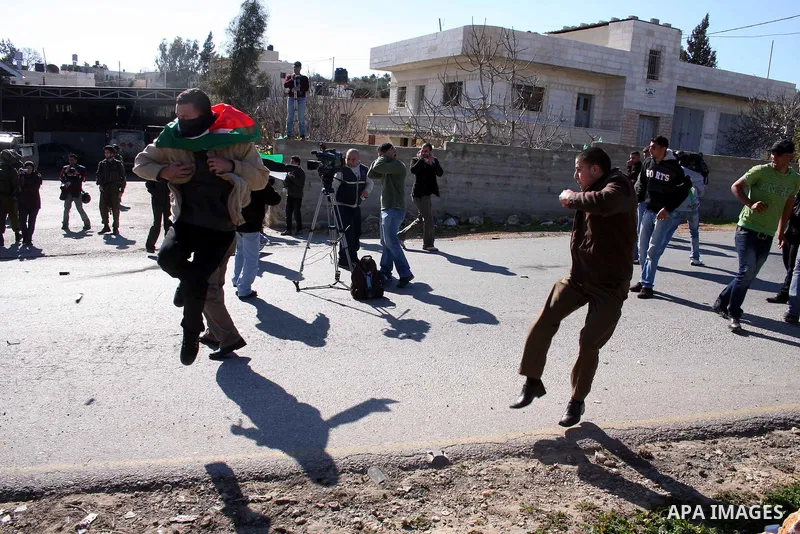 Palestinian protesters run for cover from tear gas canisters fired by Israeli soldiers during a demonstration against the expansion of the nearby Jewish settlement of Halamish in the West Bank village of Nabi Saleh, near...