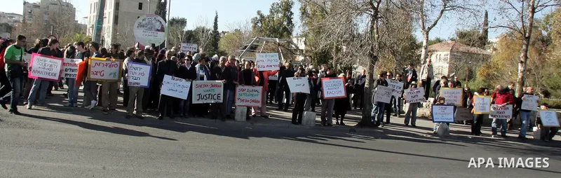 Palestinians, Israelis and foreign activists hold signs during a protest to show solidarity with Palestinian families against a Jewish settlement in the Sheikh Jarrah neighbourhood in East Jerusalem on Jan. 21, 2011. Pho...