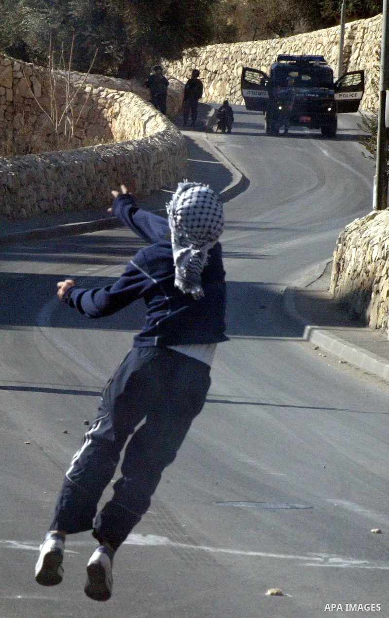 Masked Palestinian youths throw stones at Israeli forces during clashes in the Arab east Jerusalem neighbourhood of Silwan on January 21, 2011. Photo by Mahfouz Abu Turk