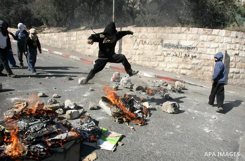 Masked Palestinian youths throw stones at Israeli forces during clashes in the Arab east Jerusalem neighbourhood of Silwan on January 21, 2011. Photo by Mahfouz Abu Turk