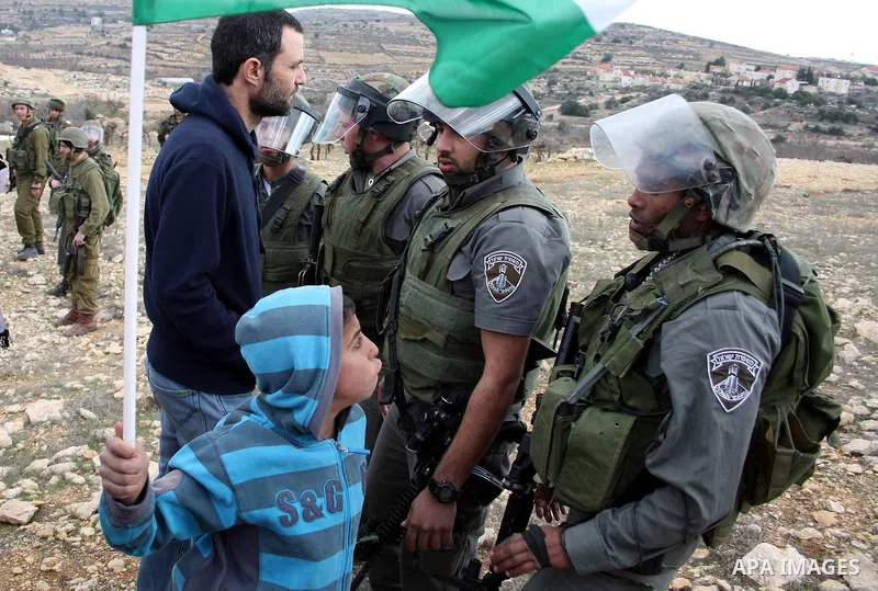 Israeli soldiers stand guard during a demonstration by Palestinian, Israeli and foreign activists against the demolishing of farm land to be used in the construction of Jewish settlements near the existing Israeli settle...