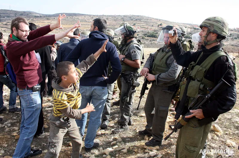 Israeli soldiers stand guard during a demonstration by Palestinian, Israeli and foreign activists against the demolishing of farm land to be used in the construction of Jewish settlements near the existing Israeli settle...