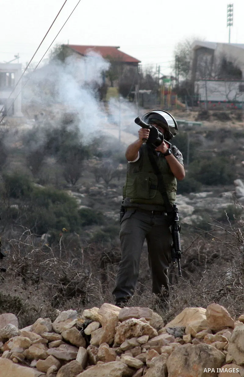An Israeli soldier fires tear gas canister towards demonstrators during a protest by Palestinian, Israeli and foreign activists against the demolishing of farm land to be used in the construction of Jewish settlements ne...