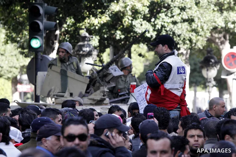 Tunisians, amongst them policemen, gather to ask for the right to form unions and better salaries as the vehicle of Tunisian interim President Fouad Mbazaa (not in picture) arrives at the government Palace in Tunis, Tuni...