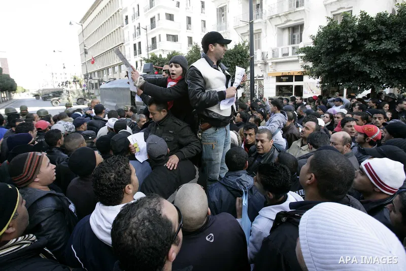 Tunisians, amongst them policemen, gather to ask for the right to form unions and better salaries as the vehicle of Tunisian interim President Fouad Mbazaa (not in picture) arrives at the government Palace in Tunis, Tuni...