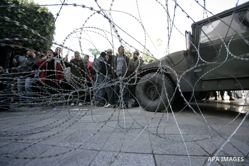 Tunisian protestors prepare to break into the barbed wire during a demonstration to demand a new government free of officials of the ousted regime of former president Zine el Abidine Ben Ali, in central Tunis, Tunisia, 2...