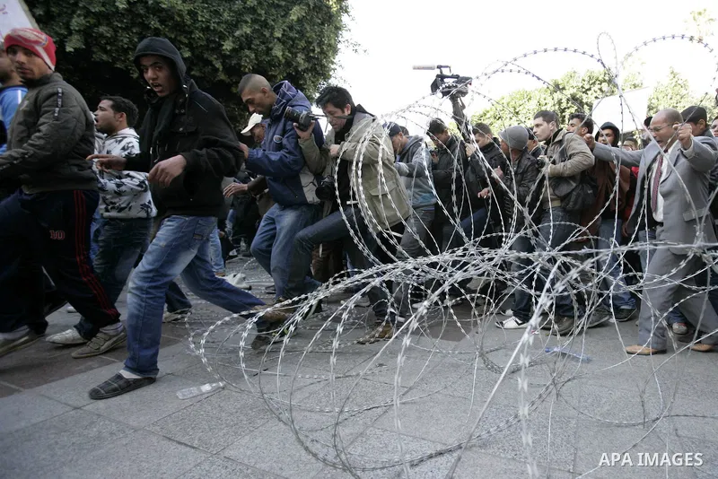 Tunisian protestors prepare to break into the barbed wire during a demonstration to demand a new government free of officials of the ousted regime of former president Zine el Abidine Ben Ali, in central Tunis, Tunisia, 2...