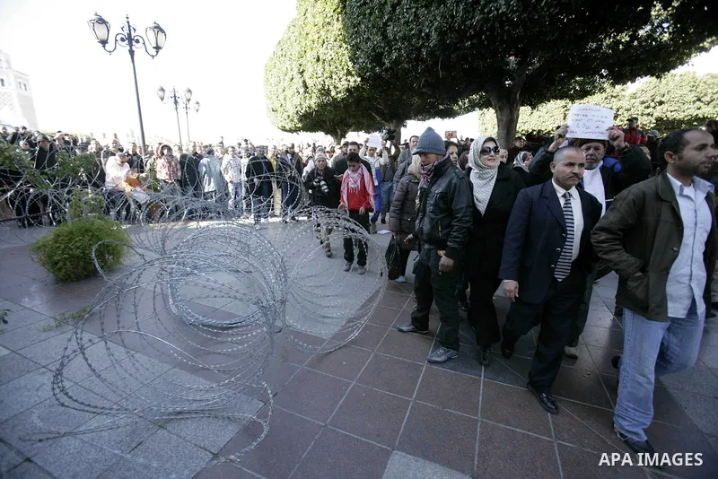 Tunisian protestors prepare to break into the barbed wire during a demonstration to demand a new government free of officials of the ousted regime of former president Zine el Abidine Ben Ali, in central Tunis, Tunisia, 2...