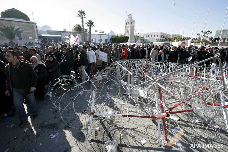Tunisian protestors prepare to break into the barbed wire during a demonstration to demand a new government free of officials of the ousted regime of former president Zine el Abidine Ben Ali, in central Tunis, Tunisia, 2...