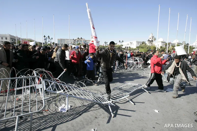 Tunisian protestors prepare to break into the barbed wire during a demonstration to demand a new government free of officials of the ousted regime of former president Zine el Abidine Ben Ali, in central Tunis, Tunisia, 2...