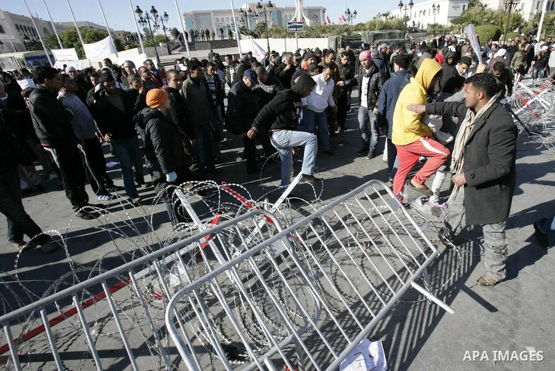 Tunisian protestors prepare to break into the barbed wire during a demonstration to demand a new government free of officials of the ousted regime of former president Zine el Abidine Ben Ali, in central Tunis, Tunisia, 2...