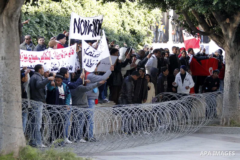 Tunisian protestors prepare to break into the barbed wire during a demonstration to demand a new government free of officials of the ousted regime of former president Zine el Abidine Ben Ali, in central Tunis, Tunisia, 2...