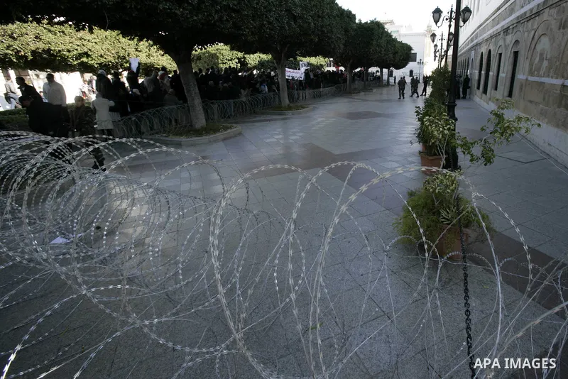 Tunisian protestors prepare to break into the barbed wire during a demonstration to demand a new government free of officials of the ousted regime of former president Zine el Abidine Ben Ali, in central Tunis, Tunisia, 2...