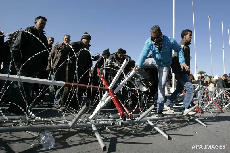 Tunisian protestors prepare to break into the barbed wire during a demonstration to demand a new government free of officials of the ousted regime of former president Zine el Abidine Ben Ali, in central Tunis, Tunisia, 2...