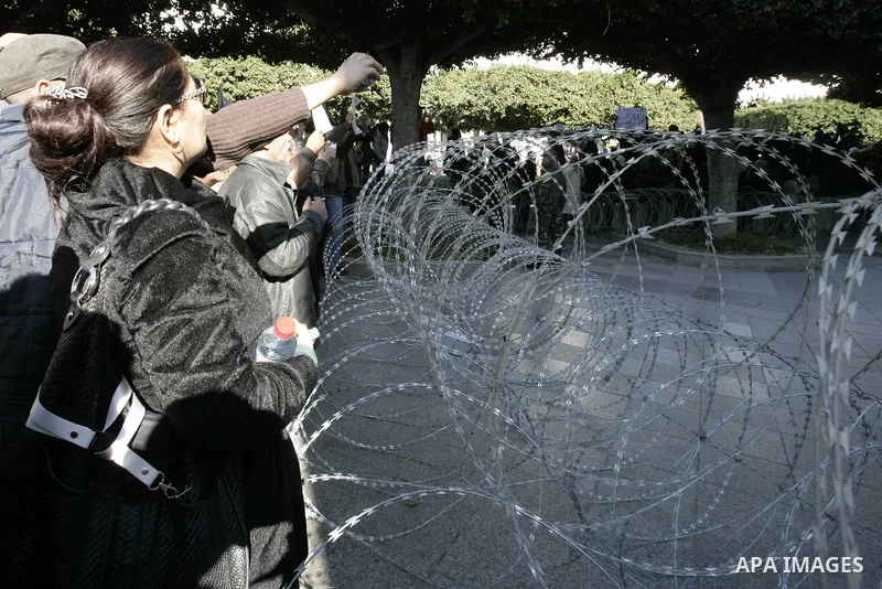 Tunisian protestors prepare to break into the barbed wire during a demonstration to demand a new government free of officials of the ousted regime of former president Zine el Abidine Ben Ali, in central Tunis, Tunisia, 2...