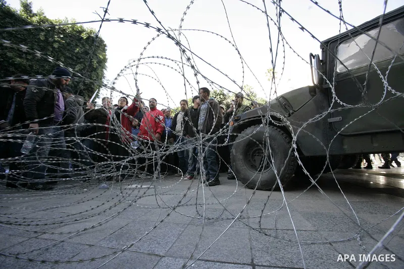 Tunisian protestors prepare to break into the barbed wire during a demonstration to demand a new government free of officials of the ousted regime of former president Zine el Abidine Ben Ali, in central Tunis, Tunisia, 2...