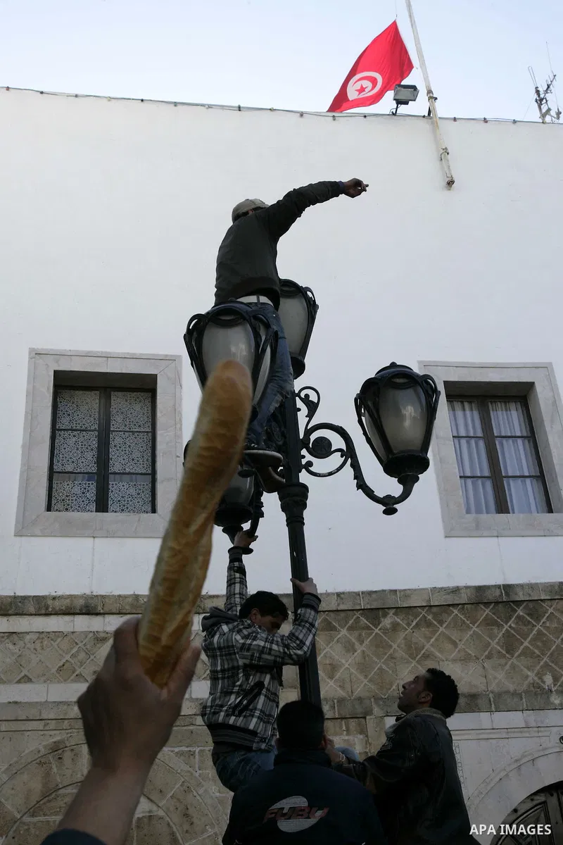 A Tunisian man holds bread during a demonstration to demand a new government free of officials of the ousted regime of former president Zine el Abidine Ben Ali, goes on in central Tunis, Tunisia, 23 January 2011. Accordi...