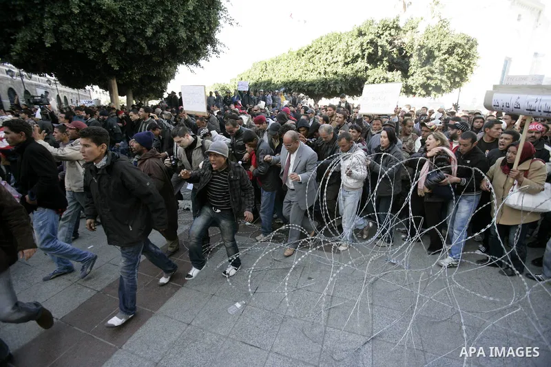 Tunisian protestors prepare to break into the barbed wire during a demonstration to demand a new government free of officials of the ousted regime of former president Zine el Abidine Ben Ali, in central Tunis, Tunisia, 2...
