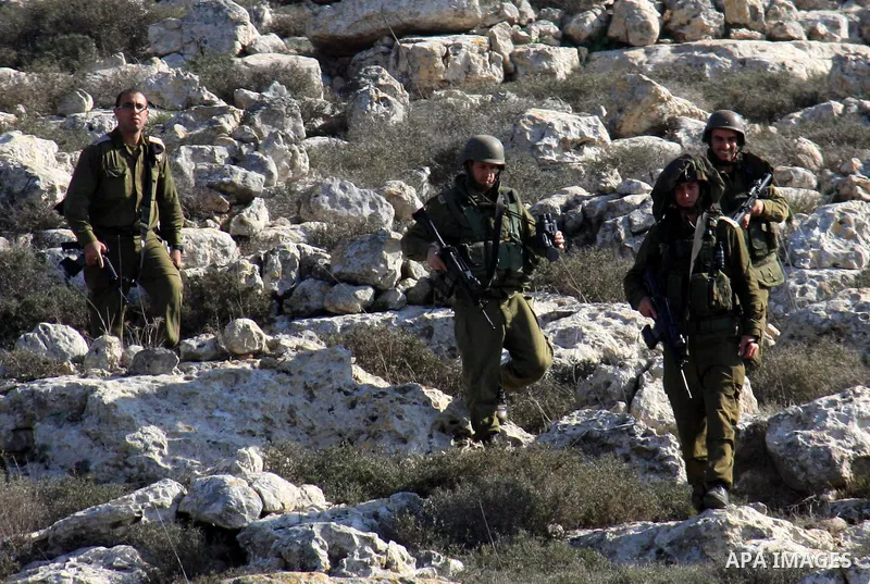 Israeli soldiers look on as Palestinian farmers plant trees during a protest against the uprooting of trees belonging to palestinians over farming land between the Jewish settlement Shiloh and the West Bank the village o...
