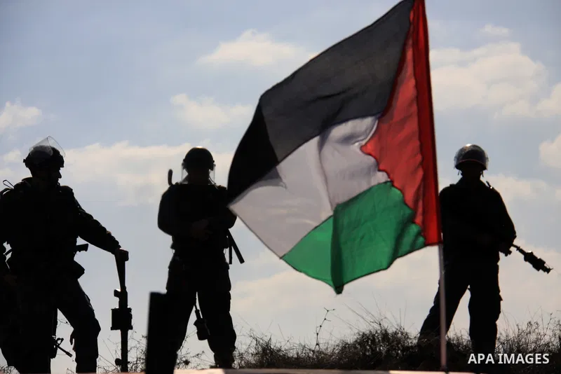 Israeli soldiers look on as Palestinian farmers plant trees during a protest against the uprooting of trees belonging to palestinians over farming land between the Jewish settlement Shiloh and the West Bank the village o...