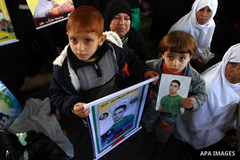 Palestinian women and children hold pictures of jailed relatives during a protest calling for the release of Palestinian prisoners from Israeli jails at the Red Cross office in Gaza City on Jan. 24, 2011. Photo by Ashraf...