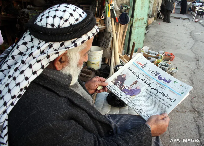 A Palestinian man reads a newspaper in front of his shop in the West Bank city of Hebron on 24 January 2011 concerning the 1,600 secret documents published by Al-Jazeera about the Israeli Palestinian negotiations. Palest...