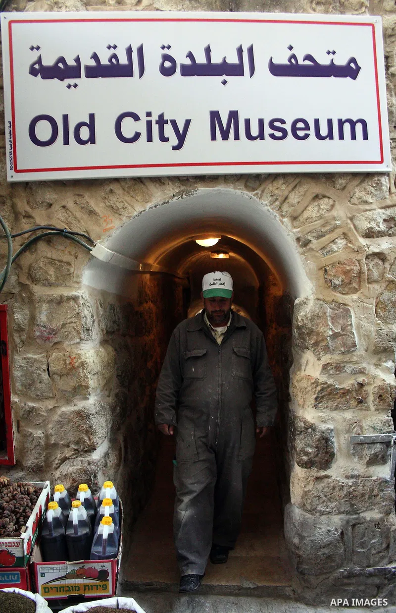 A Palestinian laborer walks near a callgraphic works during the opening of the ( Old City Museum ) in the old city of the West Bank city of Hebron on January 25, 2011. The museum located in " Haret Dari " near the Khan a...