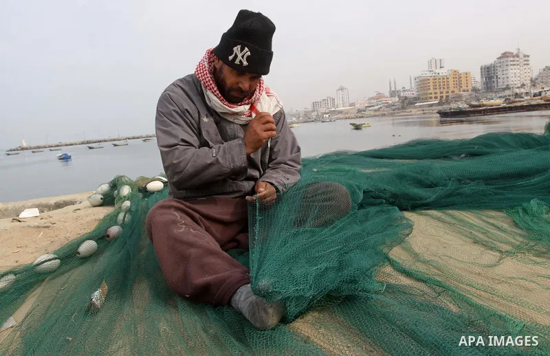 A Palestinian fisherman repairs his nets inside the port of Gaza City on Jan. 25, 2011. Fishermen, suffer from the tightening of the Israeli siege imposed on Palestinian fishermen a forbidden fishermen by Israel to enter...