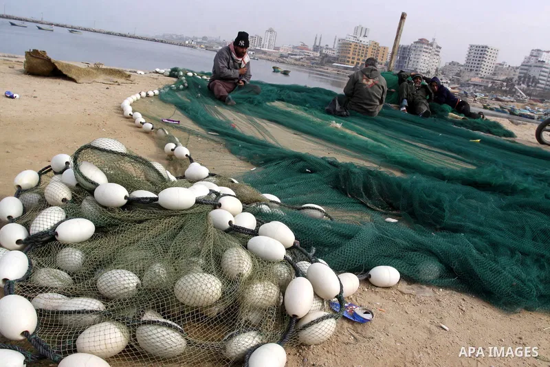 Palestinian fishermen repair their nets inside the port of Gaza City on Jan. 25, 2011. Fishermen, suffer from the tightening of the Israeli siege imposed on Palestinian fishermen a forbidden fishermen by Israel to enter...