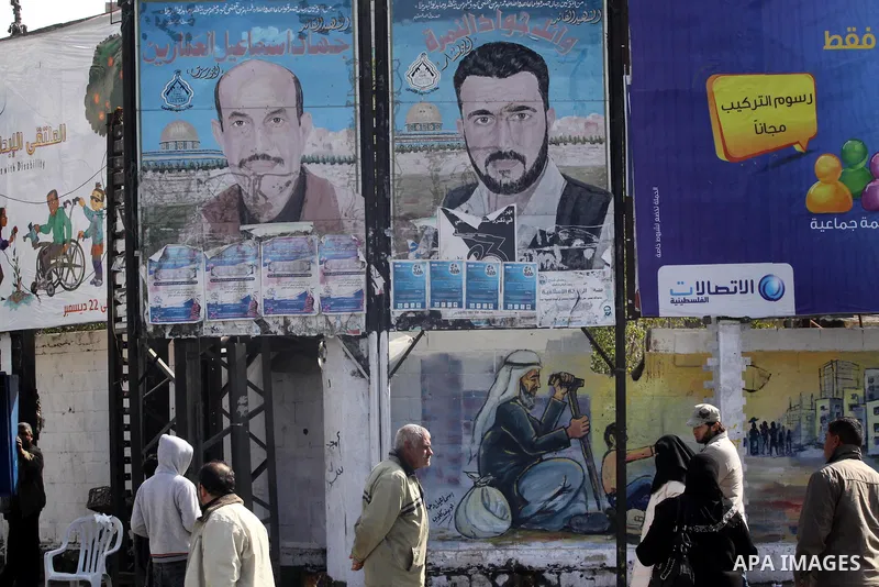 Palestinians walk past posters depicting the leaders of Al-Aqsa Martyrs Brigades, Jihad Al-Ammarin and Wail Al-Nimra, in Gaza City on Jan. 26,2011. Palestinian factions accused the Palestinian Authority in the West Bank,...