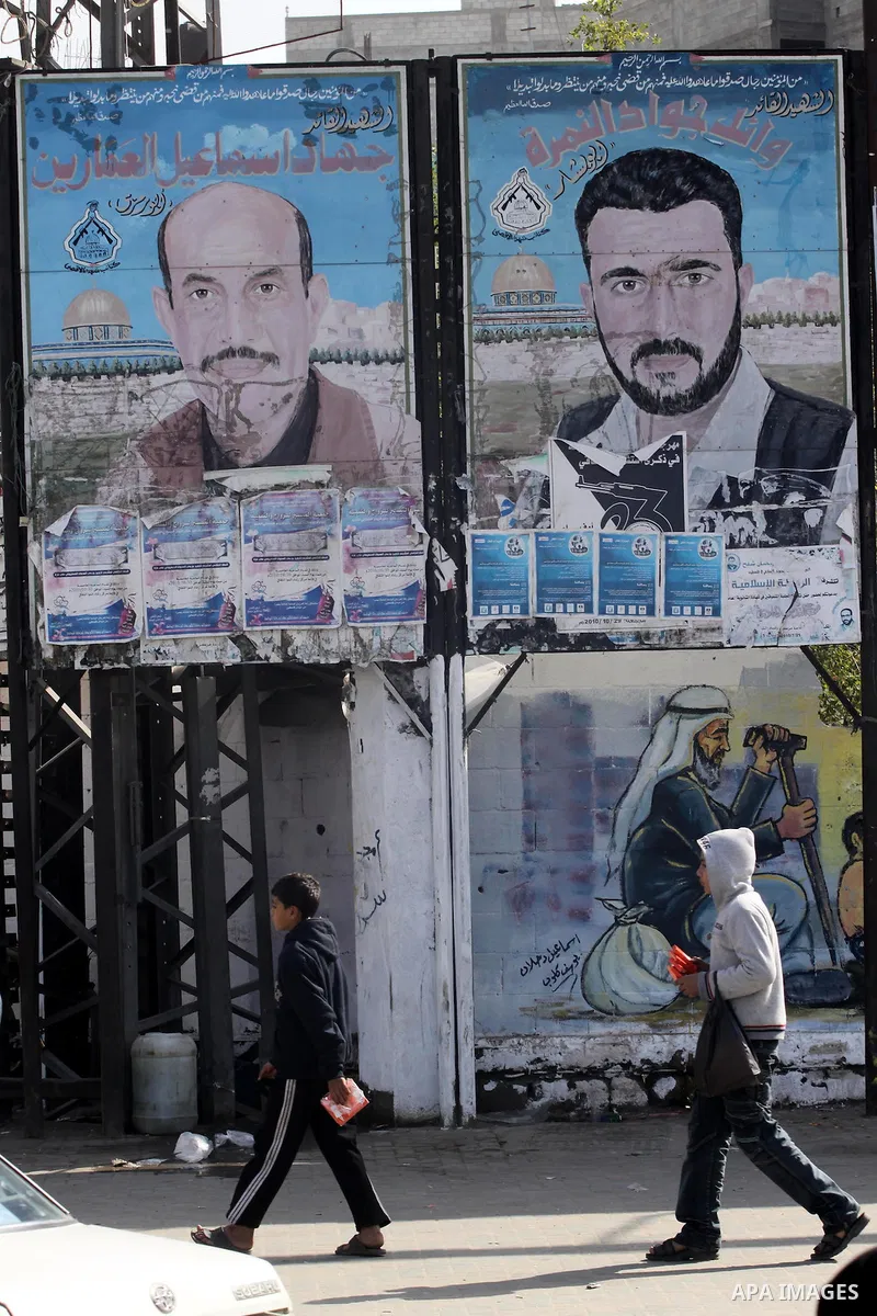 Palestinian children walk past posters depicting the leaders of Al-Aqsa Martyrs Brigades, Jihad Al-Ammarin and Wail Al-Nimra, in Gaza City on Jan. 26,2011. Palestinian factions accused the Palestinian Authority in the We...
