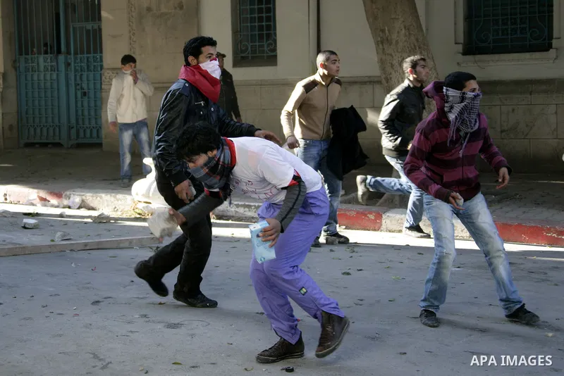 Tunisian youths hurl stones towards policemen during a demonstration against Prime Minister Mohammed Ghannouchi in front of the government palace in Tunis.Tunisia, 26 January 2011, Hundreds of defiant Tunisians camped in...