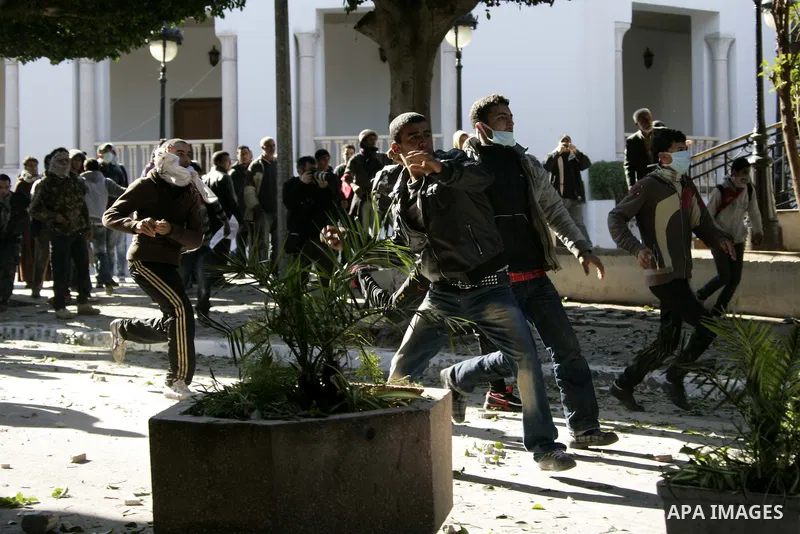 Tunisian youths hurl stones towards policemen during a demonstration against Prime Minister Mohammed Ghannouchi in front of the government palace in Tunis.Tunisia, 26 January 2011, Hundreds of defiant Tunisians camped in...
