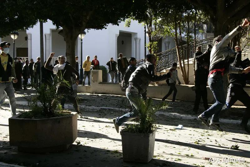 Tunisian youths hurl stones towards policemen during a demonstration against Prime Minister Mohammed Ghannouchi in front of the government palace in Tunis.Tunisia, 26 January 2011, Hundreds of defiant Tunisians camped in...