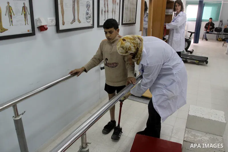 A Palestinian doctor helps a kid in his new prosthetic legs during the opening of a new prosthetics and paralysis center in coordination between the International Committee of Red Cross and the Municipality of Gaza, afte...