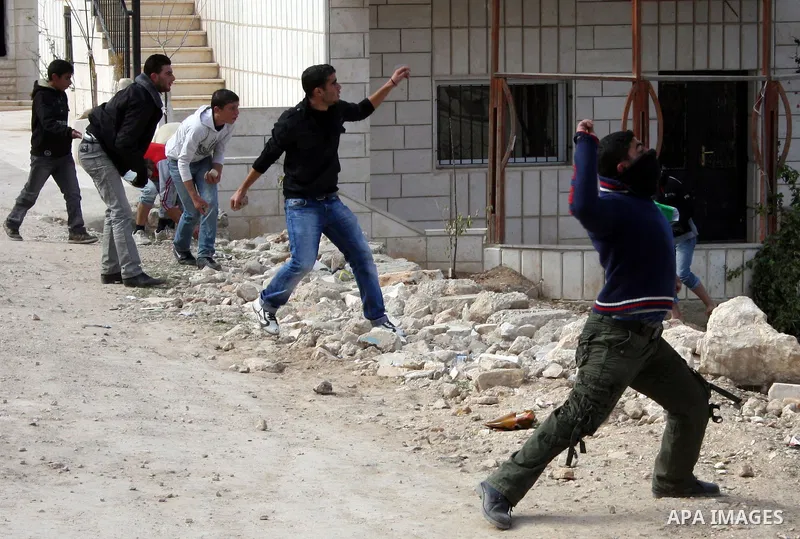 Palestinian youths hurl stones at Israeli soldiers during a demonstration by Palestinians against the demolishing of farm land to be used in the construction of Jewish settlements near the existing Israeli settlement of...