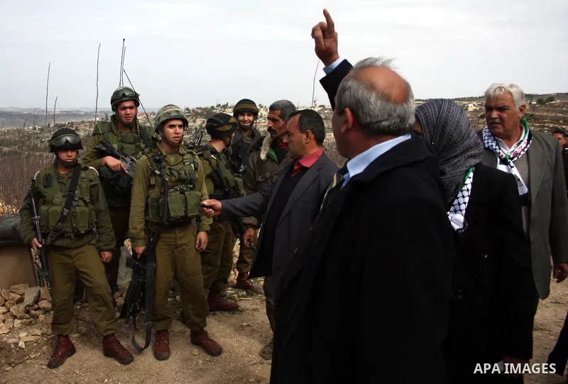 Israeli soldiers stand guard during a demonstration by Palestinian, Israeli and foreign activists against the demolishing of farm land to be used in the construction of Jewish settlements near the existing Israeli settle...