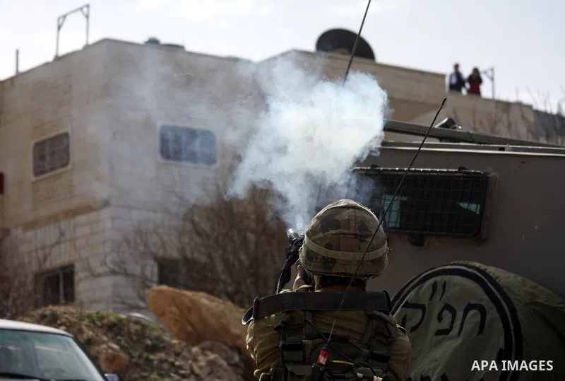 Israeli soldier fires tear gas at Palestinian stone throwers during a demonstration by Palestinians against the demolishing of farm land to be used in the construction of Jewish settlements near the existing Israeli sett...