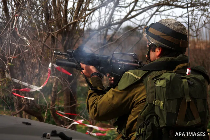 Israeli soldier fires tear gas at Palestinian stone throwers during a demonstration by Palestinians against the demolishing of farm land to be used in the construction of Jewish settlements near the existing Israeli sett...